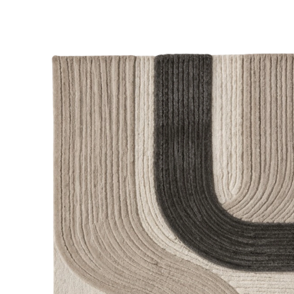 Close-up of a ribbed area rug showing a curved corner design in beige, cream, and dark charcoal gray.