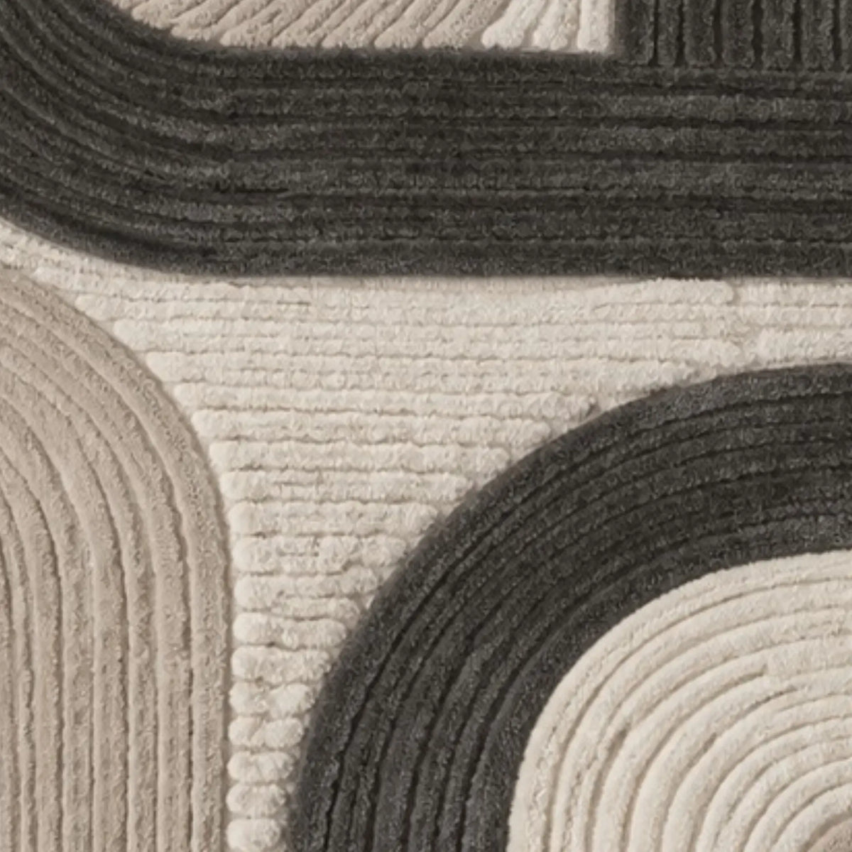 Close-up of a textured area rug with a modern geometric pattern of concentric arches in dark charcoal gray and warm cream.