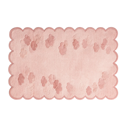 A rectangular pink rug with a scalloped edge and a scattered paw print pattern, shown on a plain white background.