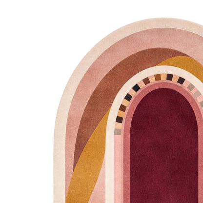 A close-up of a retro-style arched rug or textile design on a white background, featuring concentric arches in cream, blush pink, tan, mustard yellow, and deep burgundy with a small geometric border.