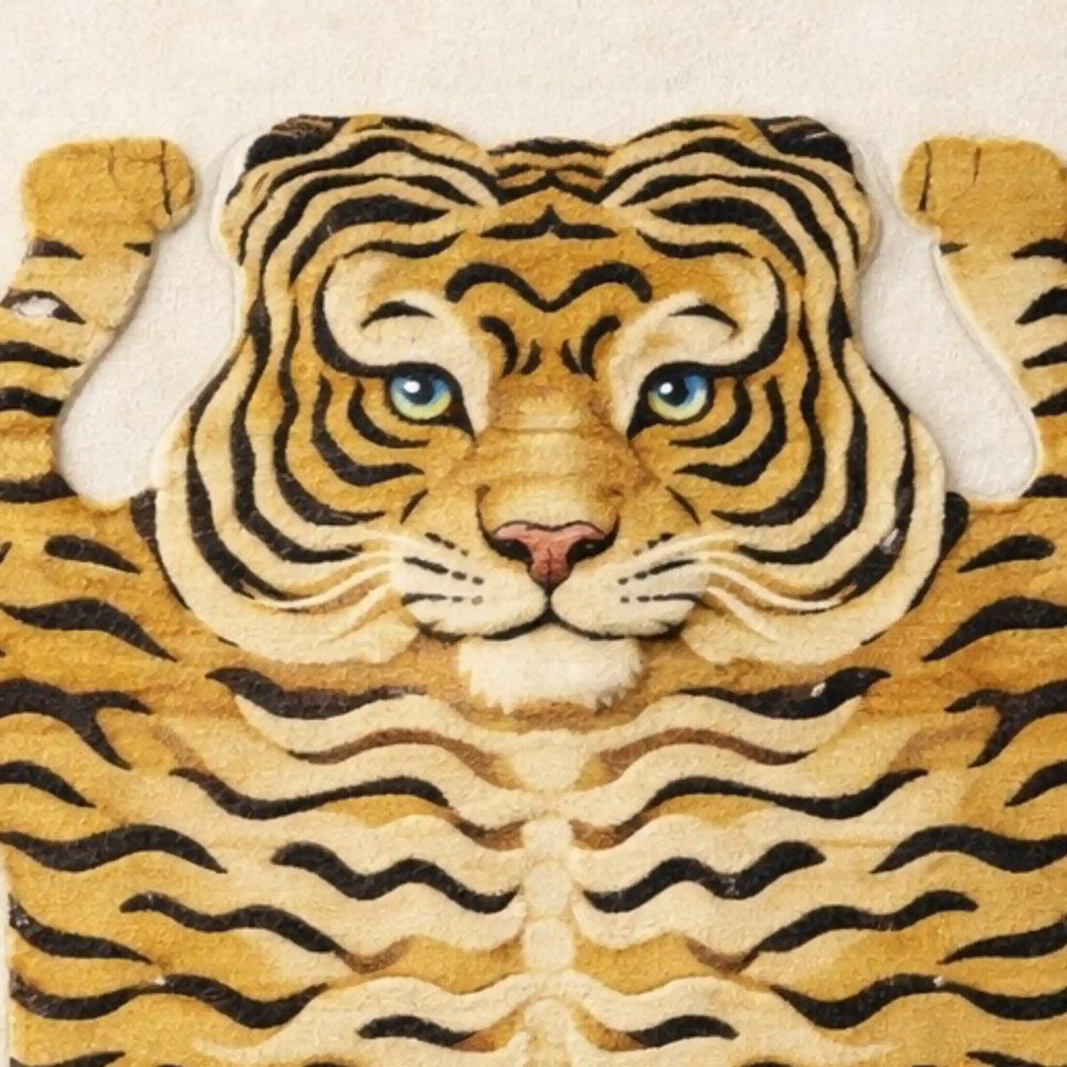 A close-up of a tiger-themed rug or textile featuring a stylized tiger face and body with black stripes on a tan and cream background, shown against a light neutral backdrop.