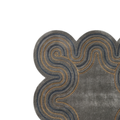 A close-up of a gray textured rug with a scalloped edge and layered wavy patterns in dark blue and tan.