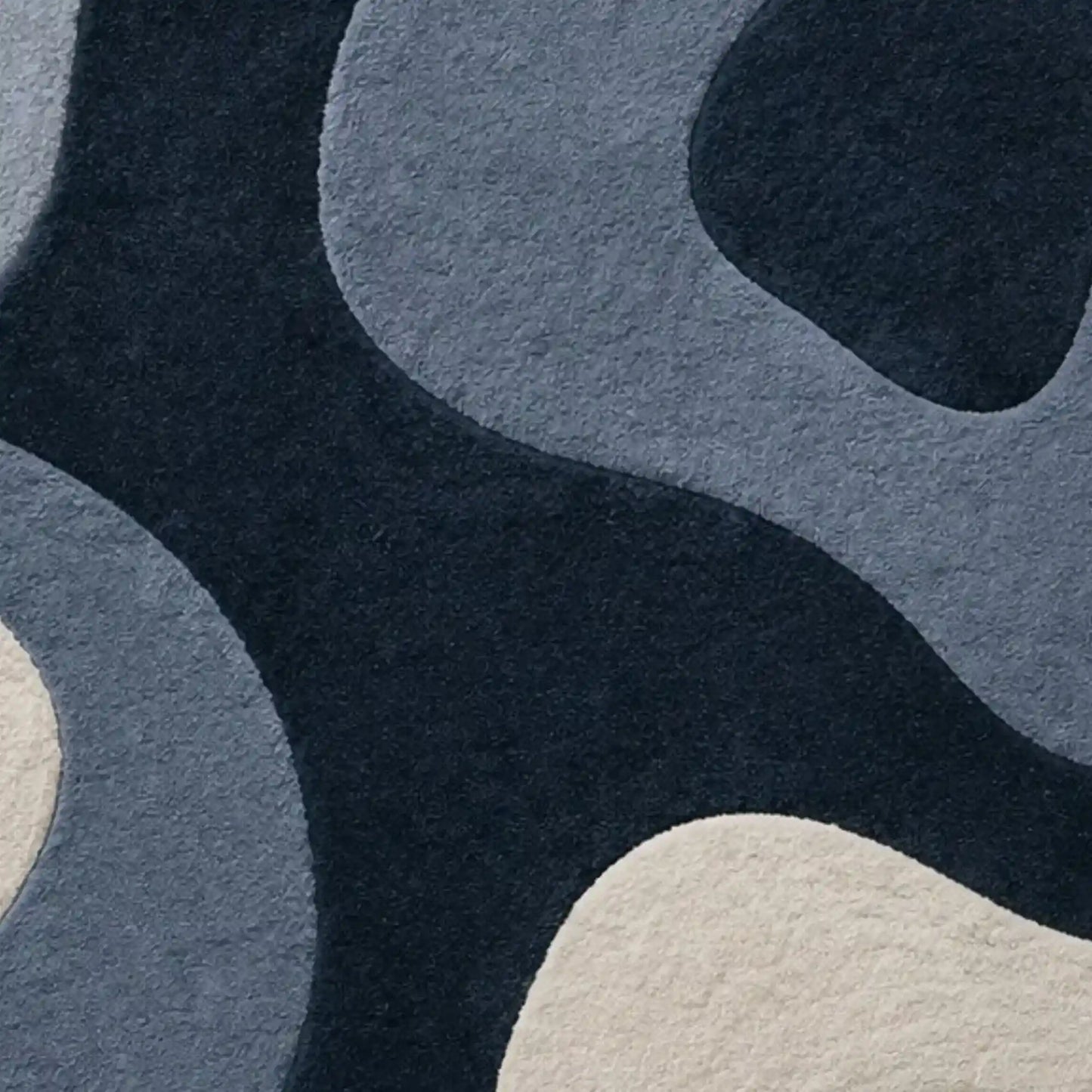 Abstract patterned area rug with organic flowing shapes in dark navy, slate blue, and cream.