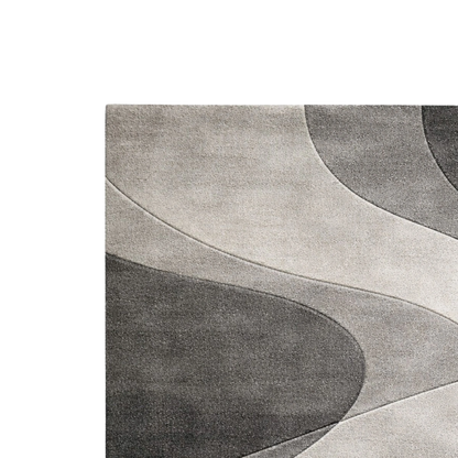 A close-up of a modern abstract area rug with flowing, wavy organic shapes in shades of gray, charcoal, and light taupe on a white background.