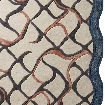 Close-up of a patterned rug or textile with an abstract interlocking curved design in dark charcoal, warm terracotta, and a blue border on a cream background.