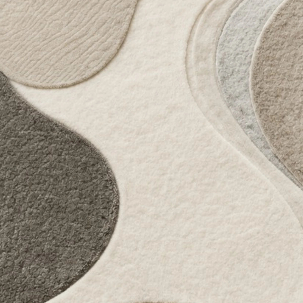 A close-up of a textured area rug with an abstract organic pattern in cream, light gray, taupe, and charcoal gray.
