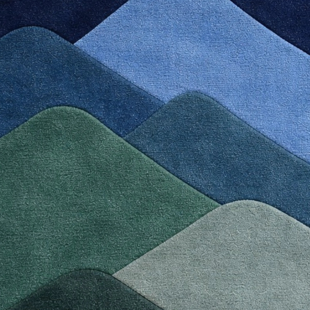 A close-up of layered, rounded mountain-like shapes in shades of blue, green, and pale gray, showing a soft textured surface.