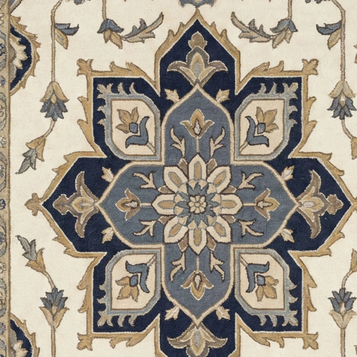 A close-up of an ornate traditional rug pattern featuring a central medallion in navy blue, dusty blue, beige, and muted gold.