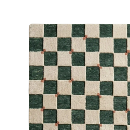 A close-up of a woven rug with a green and cream checkerboard pattern, showing the texture of the fibers and small brown accent squares at the intersections.