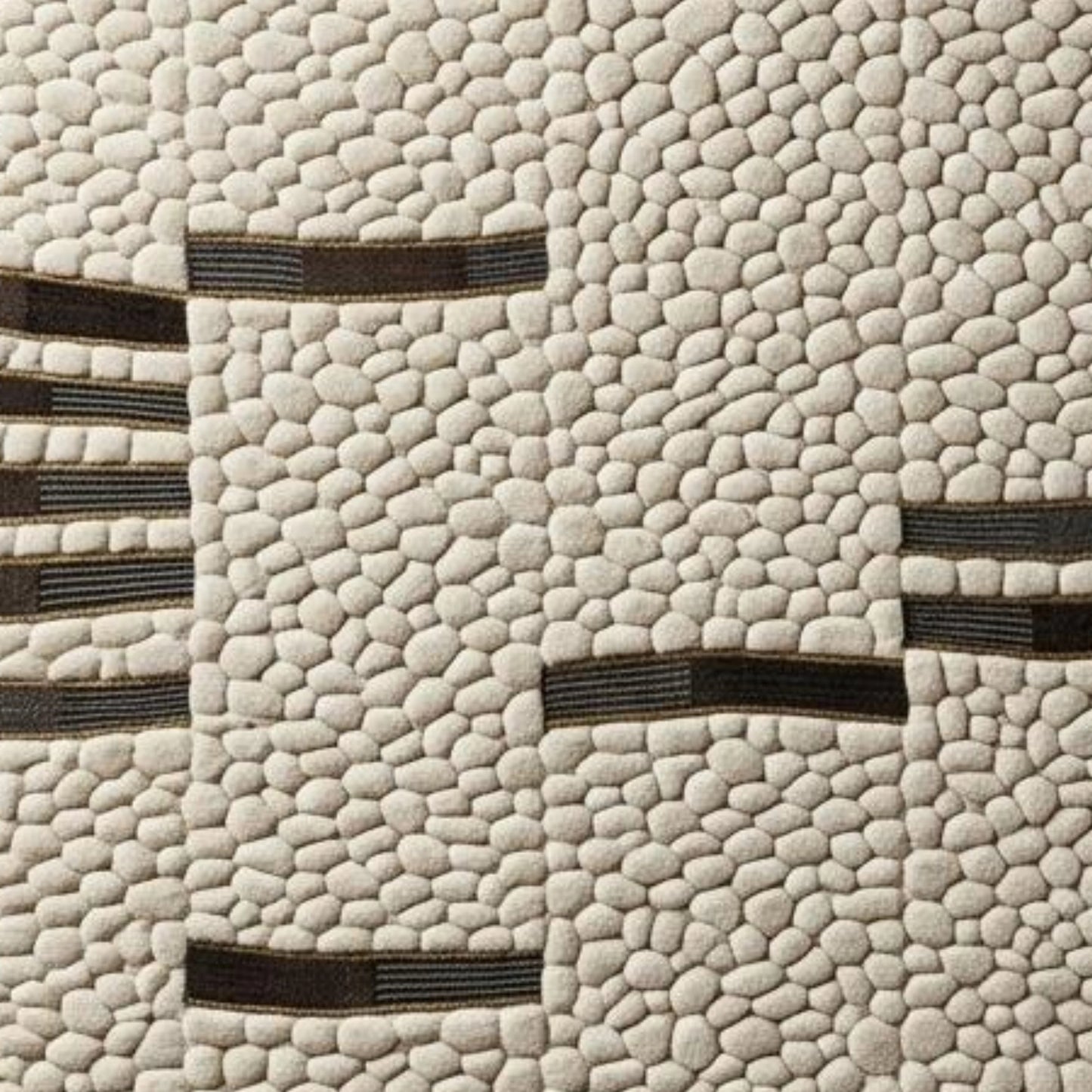 A close-up of a textured fabric or wallpaper featuring a cream-colored pebble pattern with dark brown horizontal stripe accents.