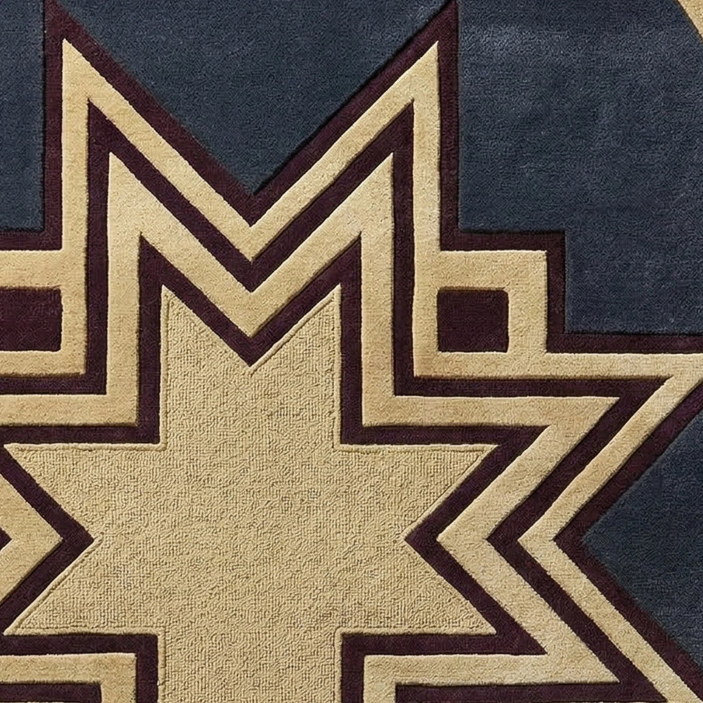 Close-up of a geometric patterned textile, likely a rug or fabric, featuring a large tan star shape outlined in dark brown, set against a dark navy blue background.