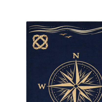 A close-up of a navy blue rug featuring a gold compass rose, a gold rope knot motif, and two small birds above wavy lines, shown against a white background.