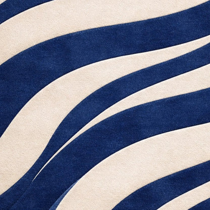 A close-up of a fabric or material swatch with bold, wavy diagonal stripes in deep navy blue and warm off-white.