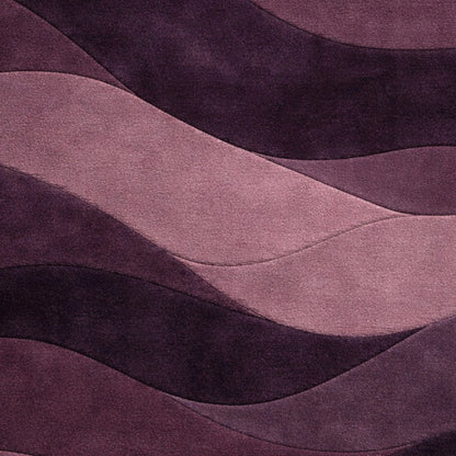 A close-up of a wavy, layered fabric or material surface in shades of purple and dusty pink, with a soft textured finish.