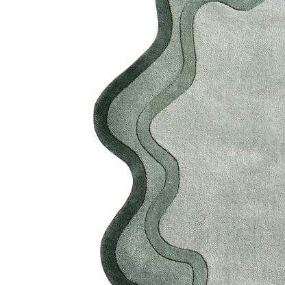 A close-up of a textured area rug with a wavy, layered border design in shades of sage green and gray on a white background.