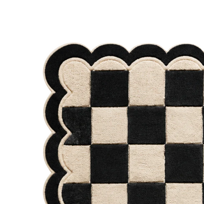 Detailed view of black and ivory scalloped rug border featuring layered curved edges, cream piping, and premium hand-tufted wool texture.